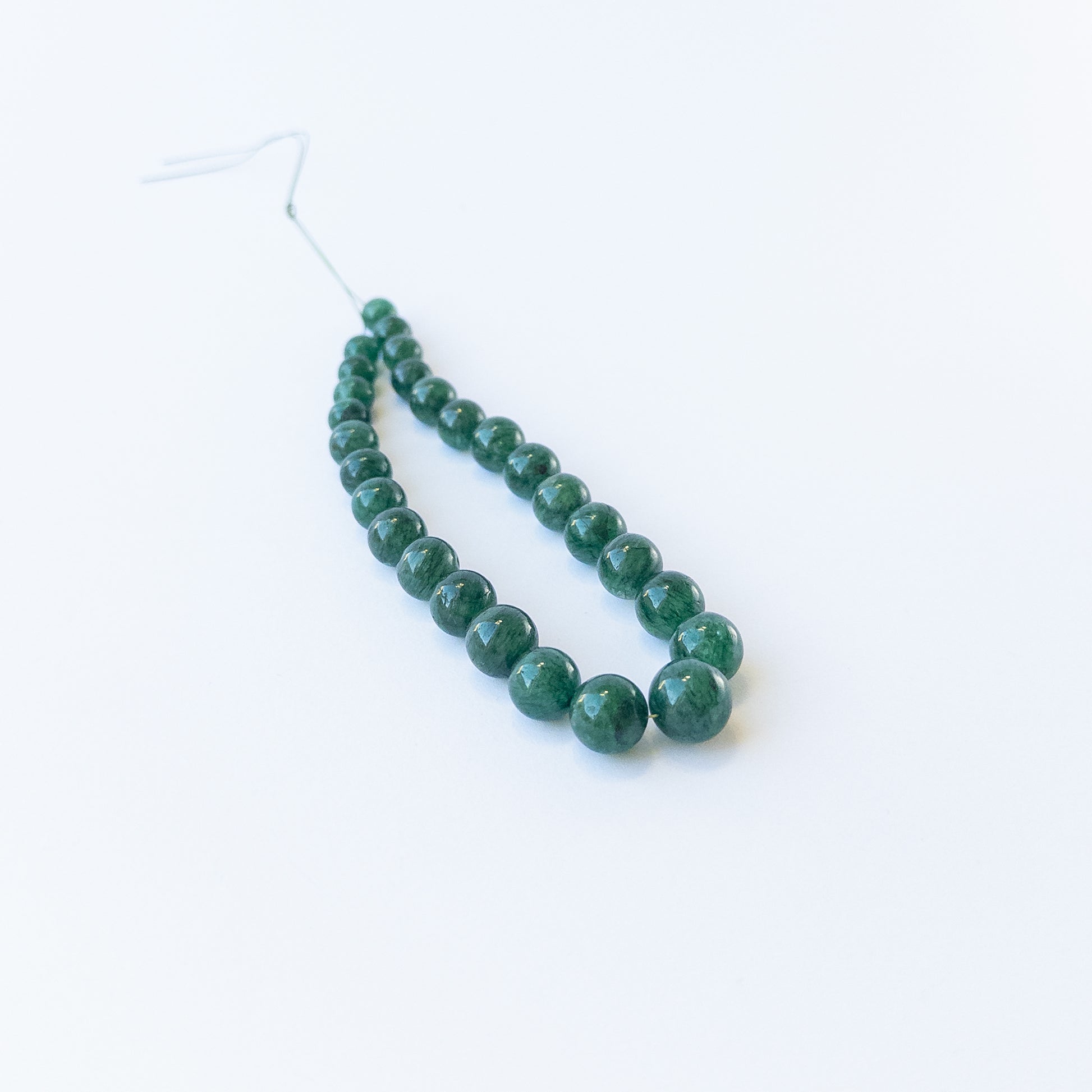 Authentic Emerald stone beads in smooth round cut arranged neatly for DIY jewellery making.