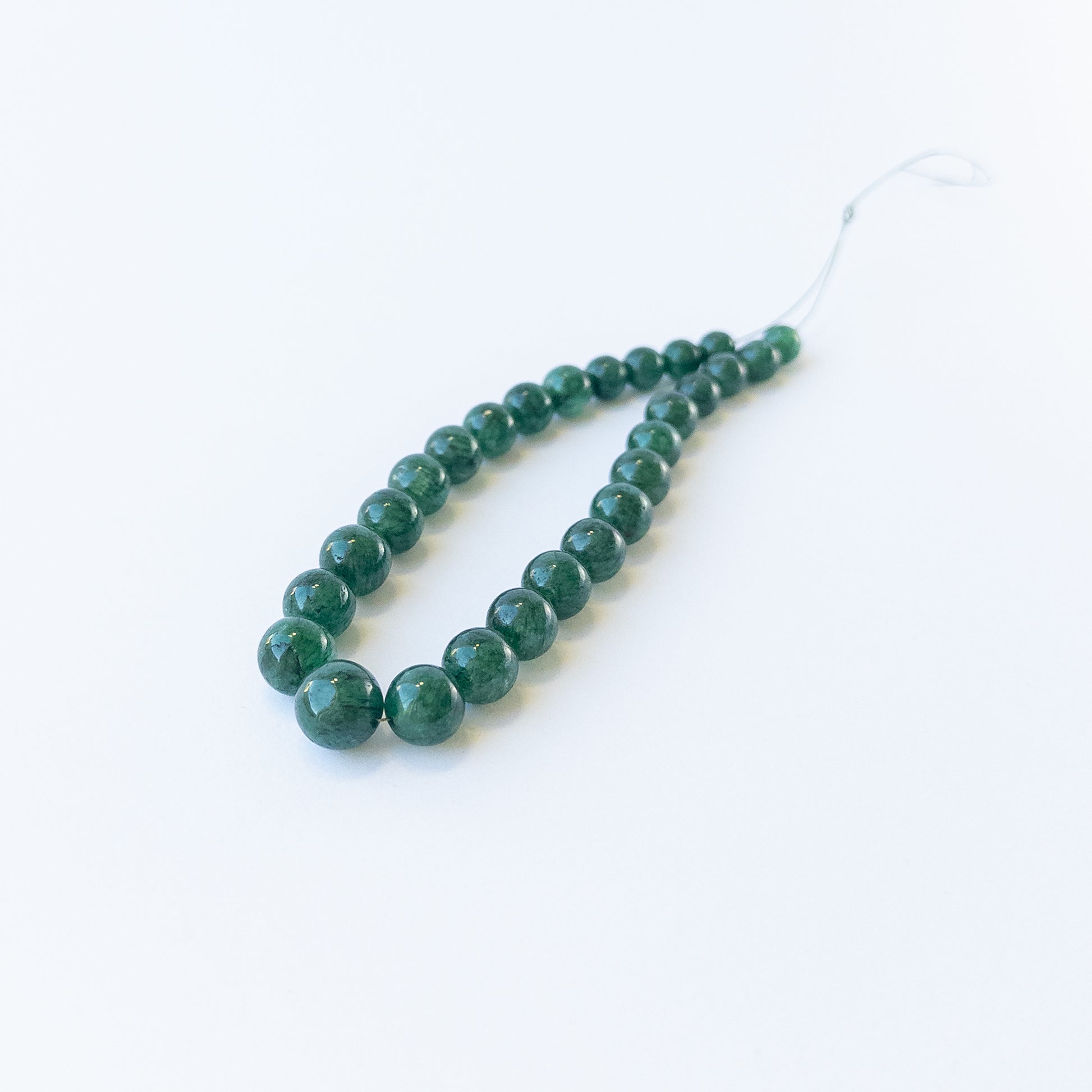 Genuine Emerald smooth round gemstone beads showcasing rich green colour and polished shine.