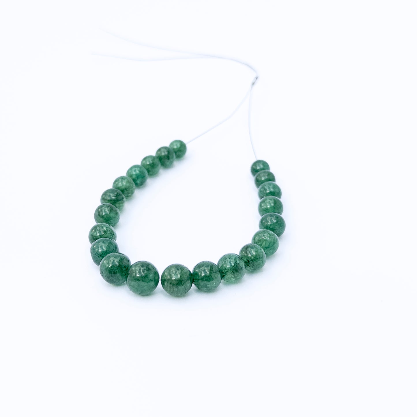 Emerald smooth round gemstone beads arranged in a strand, showcasing rich green tones and polished shine.