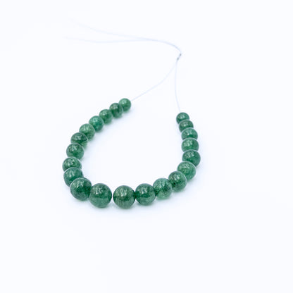 Emerald smooth round gemstone beads arranged in a strand, showcasing rich green tones and polished shine.