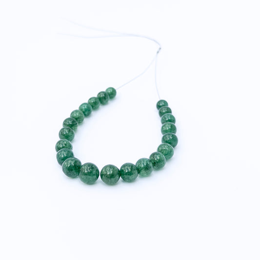 Emerald smooth round gemstone beads arranged in a strand, showcasing rich green tones and polished shine.