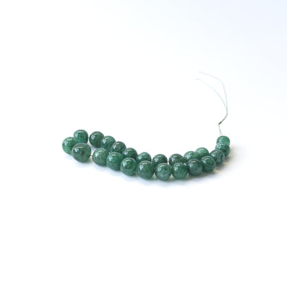 Genuine Emerald gemstone beads showcasing smooth round cuts arranged neatly in 23‑piece sets.
