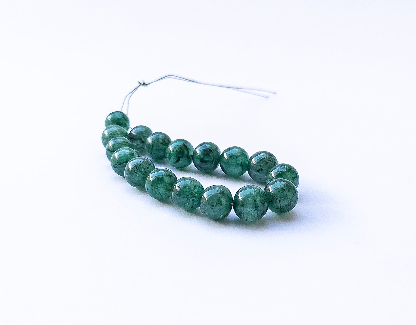 Close‑up of Emerald smooth round beads with rich green tones and glossy shine.