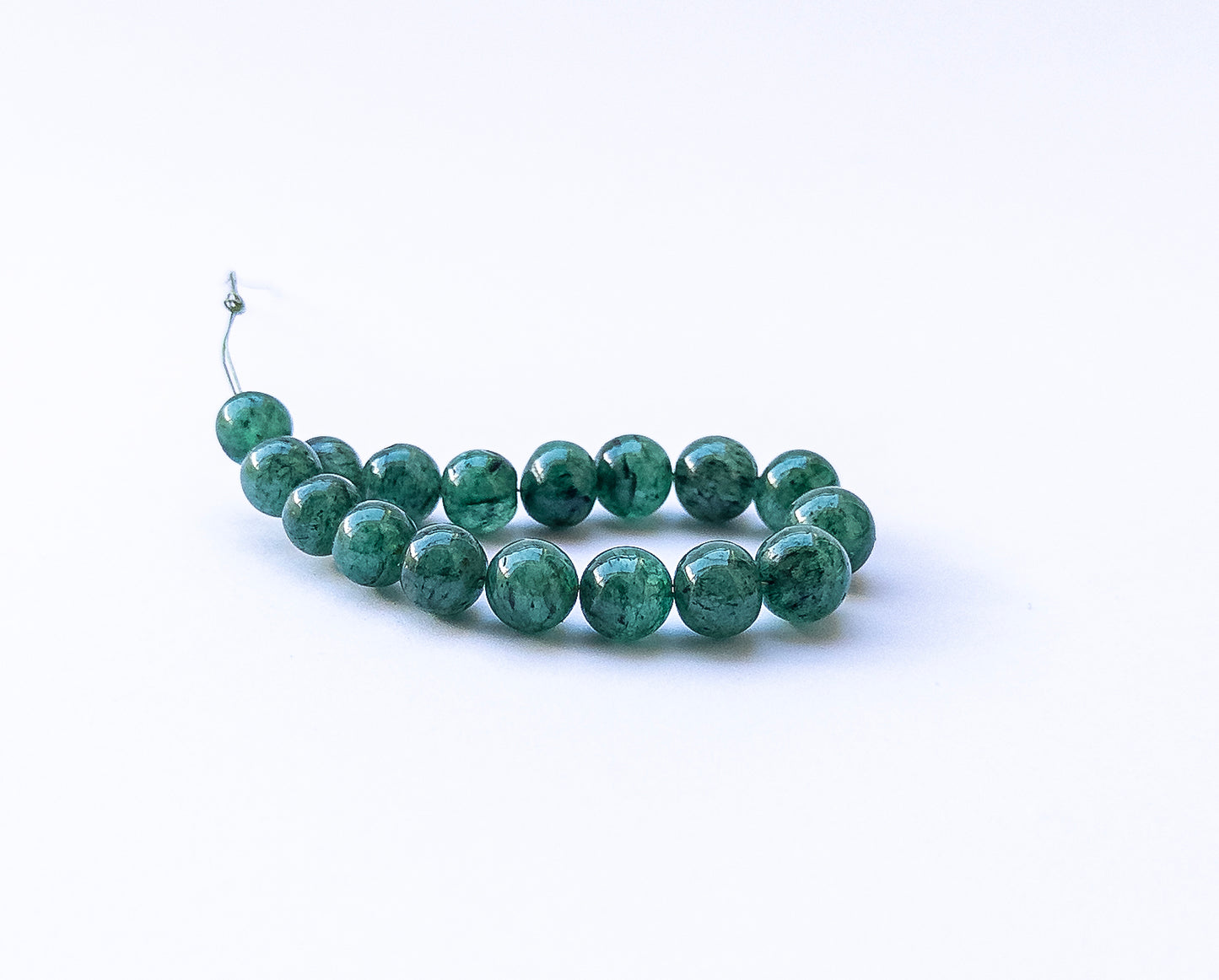 Emerald smooth round beads arranged neatly, highlighting their 7.5–9mm size.