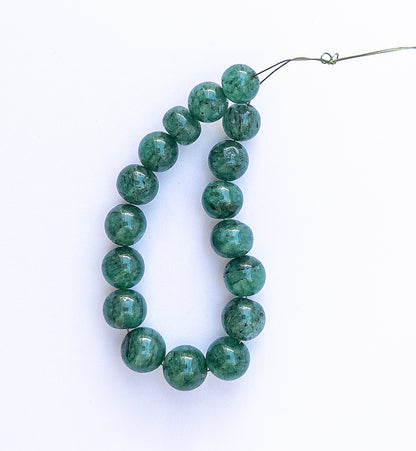 Polished Emerald round beads showing vibrant green hues and refined shaping.