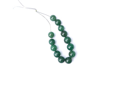 Emerald smooth round beads arranged neatly, highlighting their 9–10mm size.