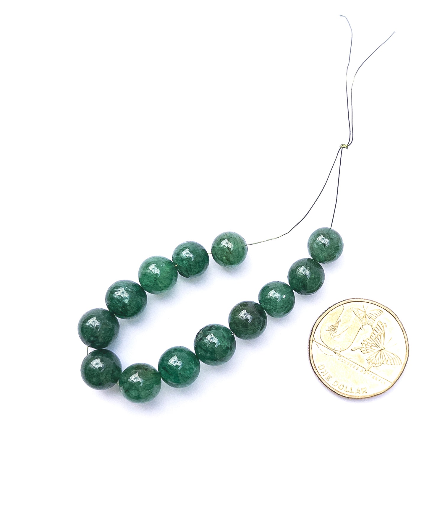 Polished Emerald round beads showing vibrant green hues and refined shaping.
