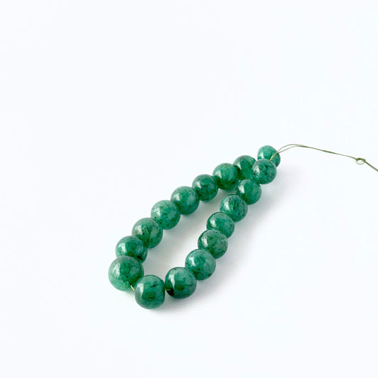 Smooth round Emerald stone beads arranged neatly, highlighting their polished finish and handmade jewellery component quality.