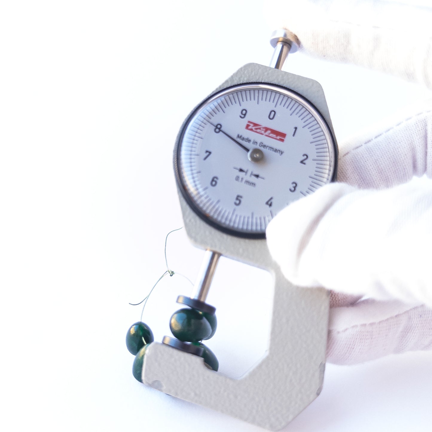 A dial gauge measuring the Emerald smooth briolette 6.7–8.5mm beads.