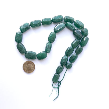 A coin is placed near delicate strands of Emerald beads for scale.