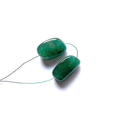 Smooth tumble emerald beads glowing with intense green clarity and balanced proportions.
