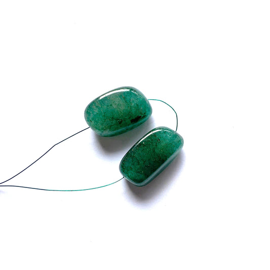 Smooth tumble emerald beads glowing with intense green clarity and balanced proportions.