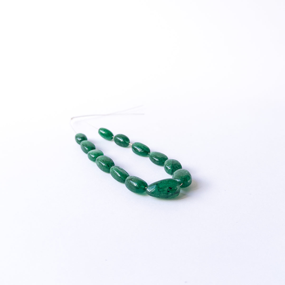 Close‑up of Emerald smooth tumble beads revealing polished texture, clarity and handcrafted quality.