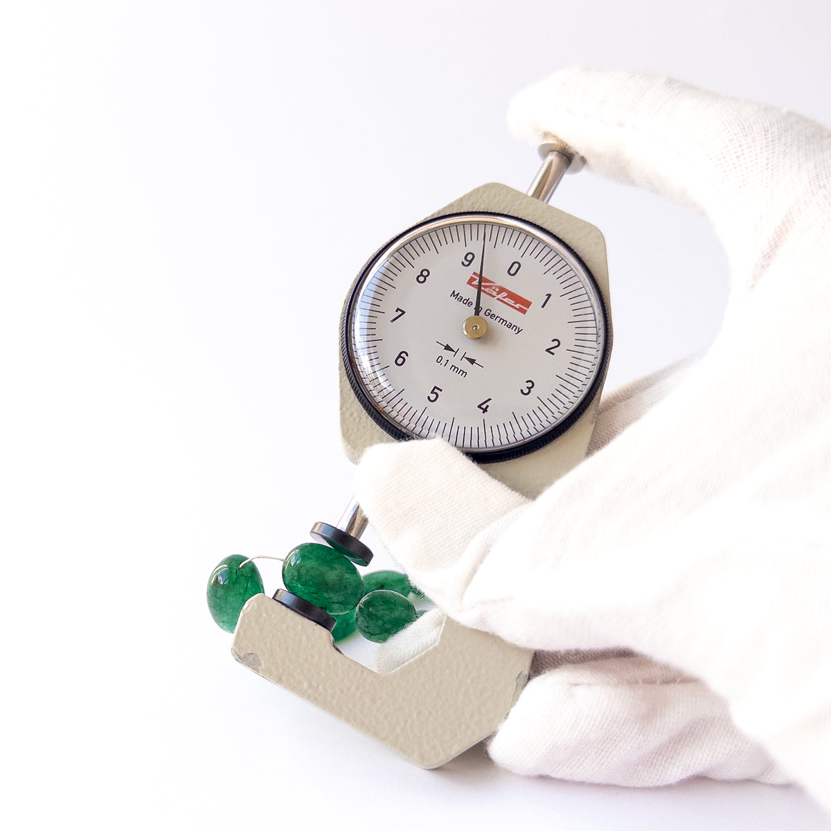 A dial gauge measures the Emerald smooth tumble 6.8–8.5mm gemstone.