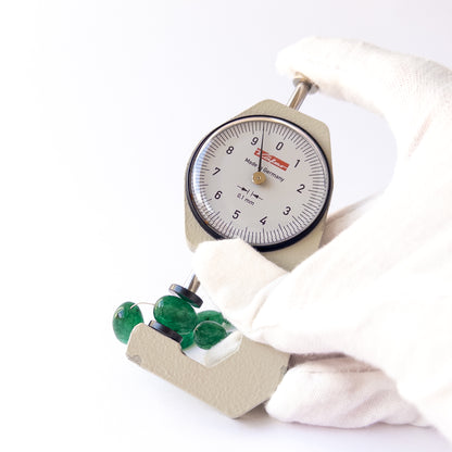 A dial gauge measures the Emerald smooth tumble 6.8–8.5mm gemstone.