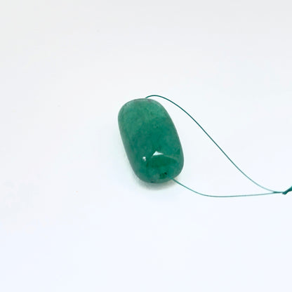 Single emerald tumbled drilled bead displayed to showcase shape and deep green tone.