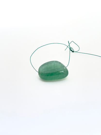 Emerald tumble bead photographed to show its organic form and suitability for jewellery making.