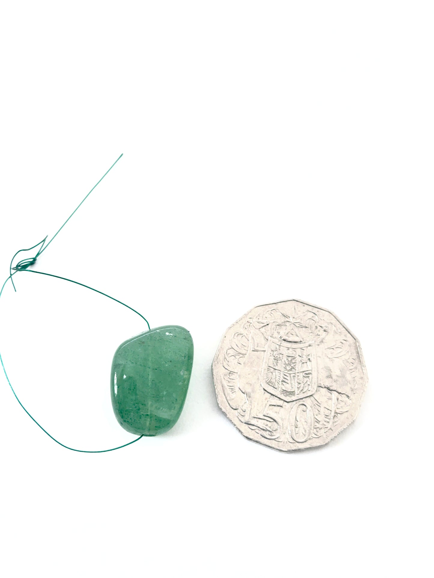 Emerald tumbled drilled stone arranged to highlight gemstone quality and colour depth.