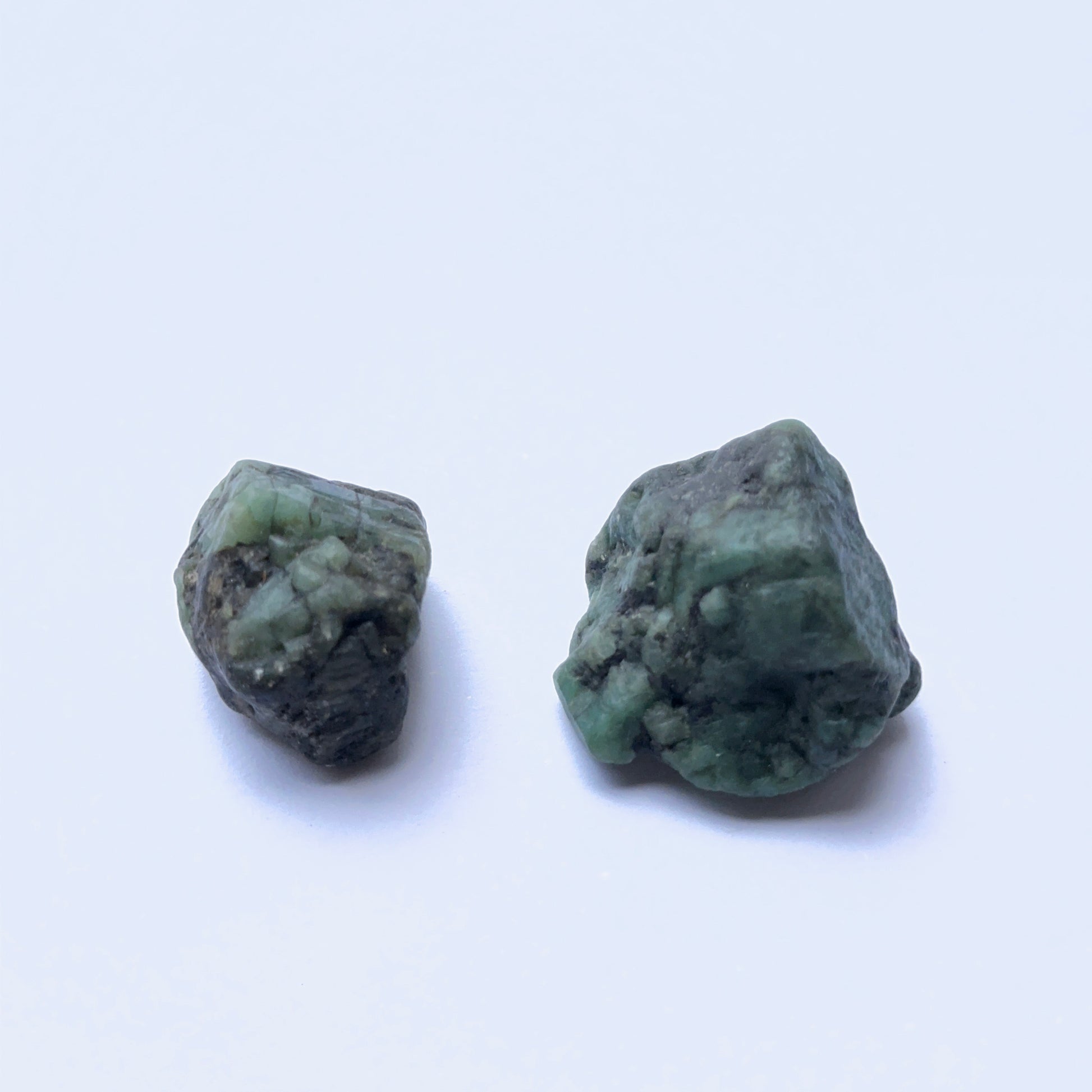 Close‑up of emerald undrilled stones on white background.
