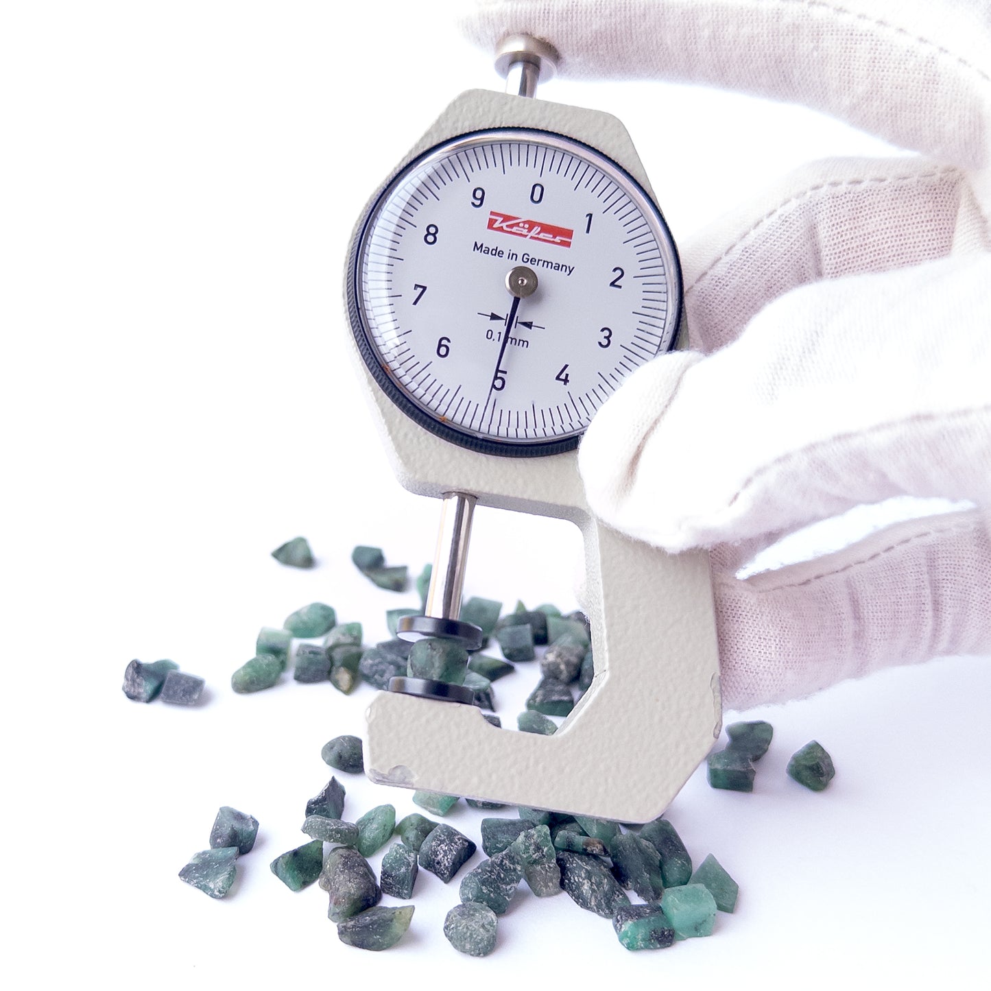 A dial gauge measures the Emerald rough 5–6mm gemstone.