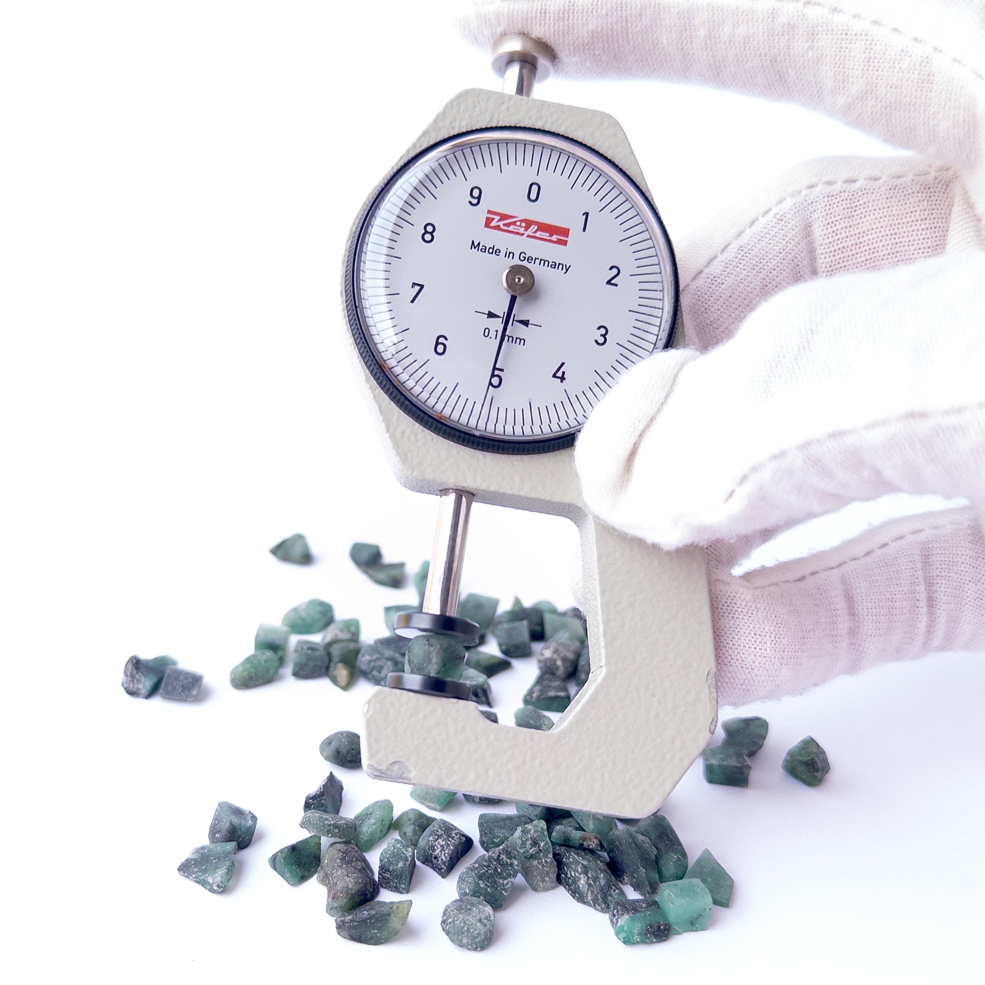 A dial gauge measures the Emerald rough 5–6mm gemstone.