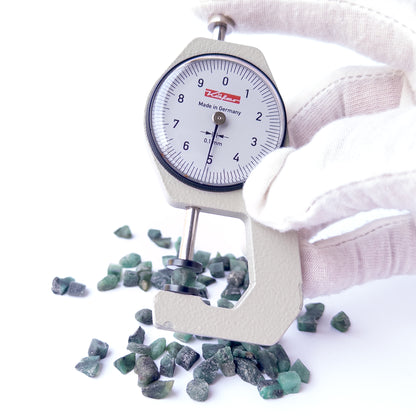 A dial gauge measures the Emerald rough 5–6mm gemstone.