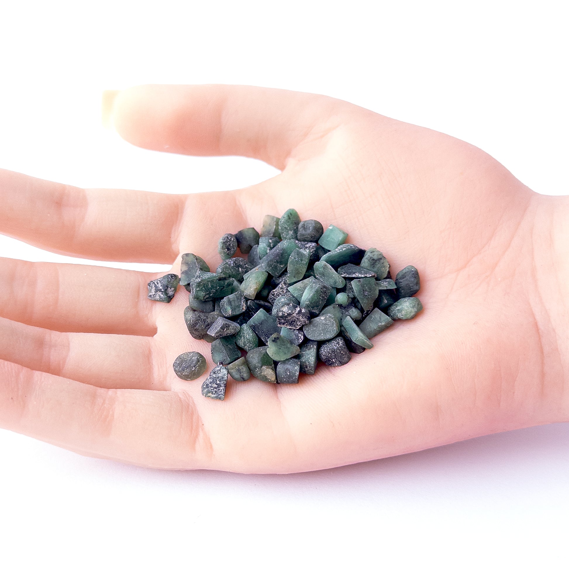A person holds delicate pieces of Emerald rough, showcasing their natural design.