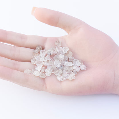 A person holds delicate pieces of Herkimer Diamonds rough, showcasing their raw crystal design.