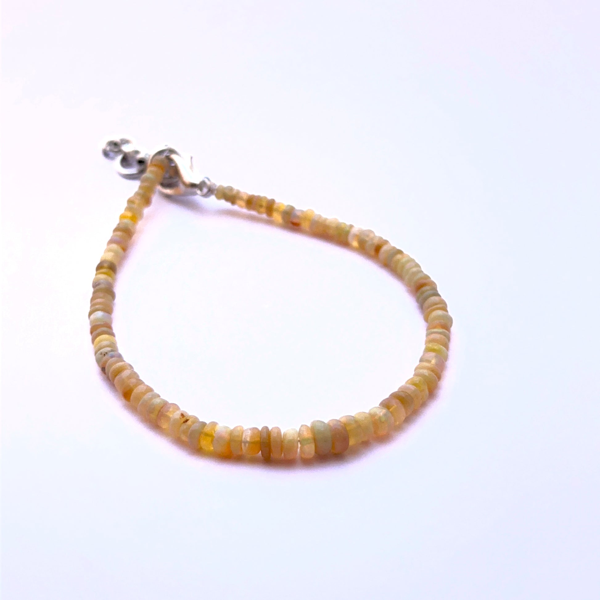 Close‑up of smooth opal rondelle beads arranged on a polished bracelet.