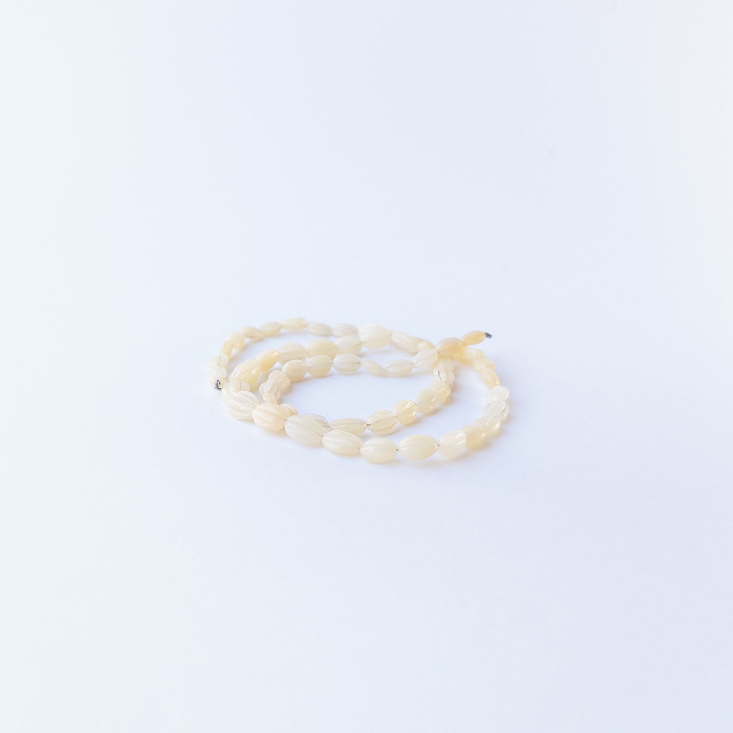 Handmade jewellery components featuring carved Ethiopian Opal oval beads in a neatly arranged strand.