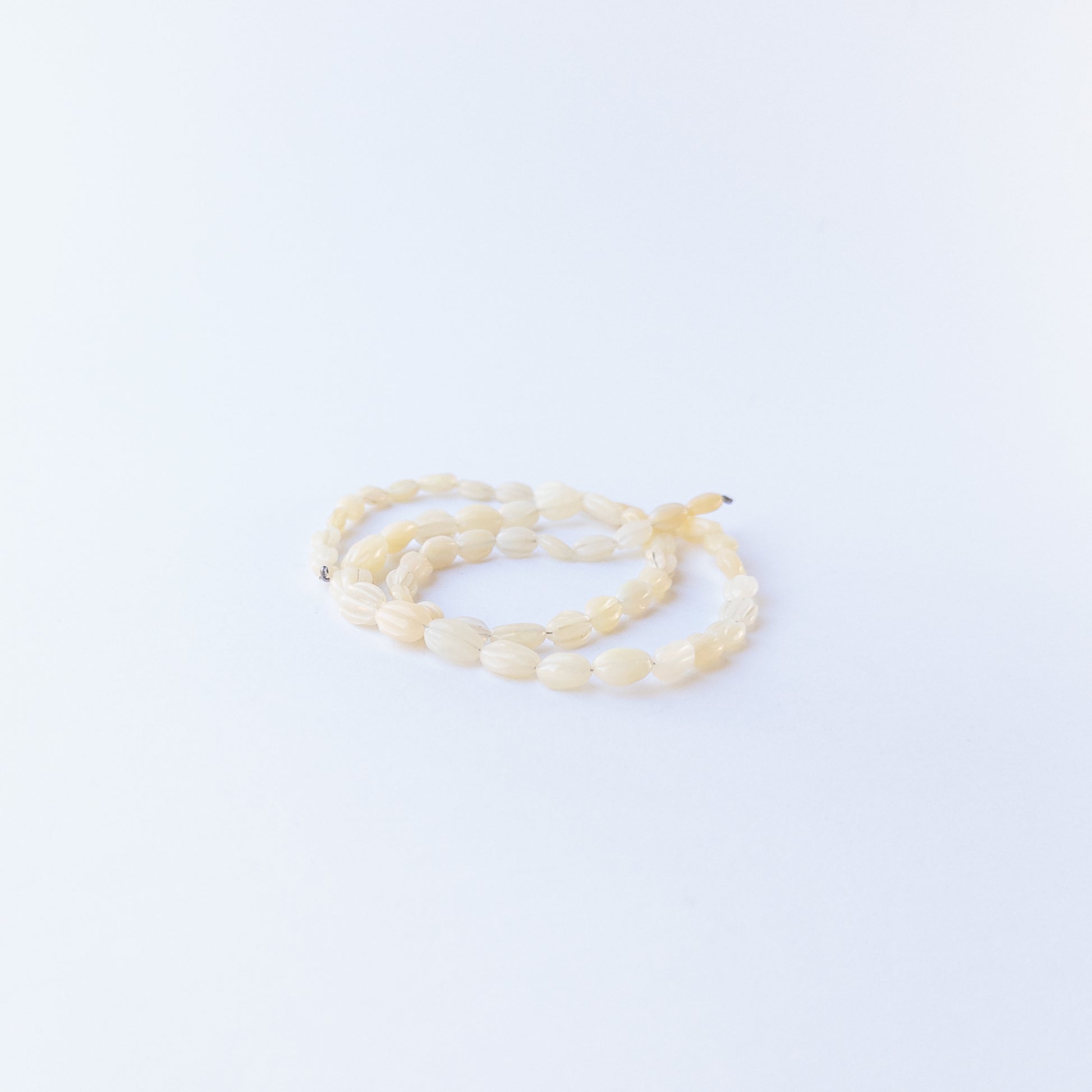 Handmade jewellery components featuring carved Ethiopian Opal oval beads in a neatly arranged strand.