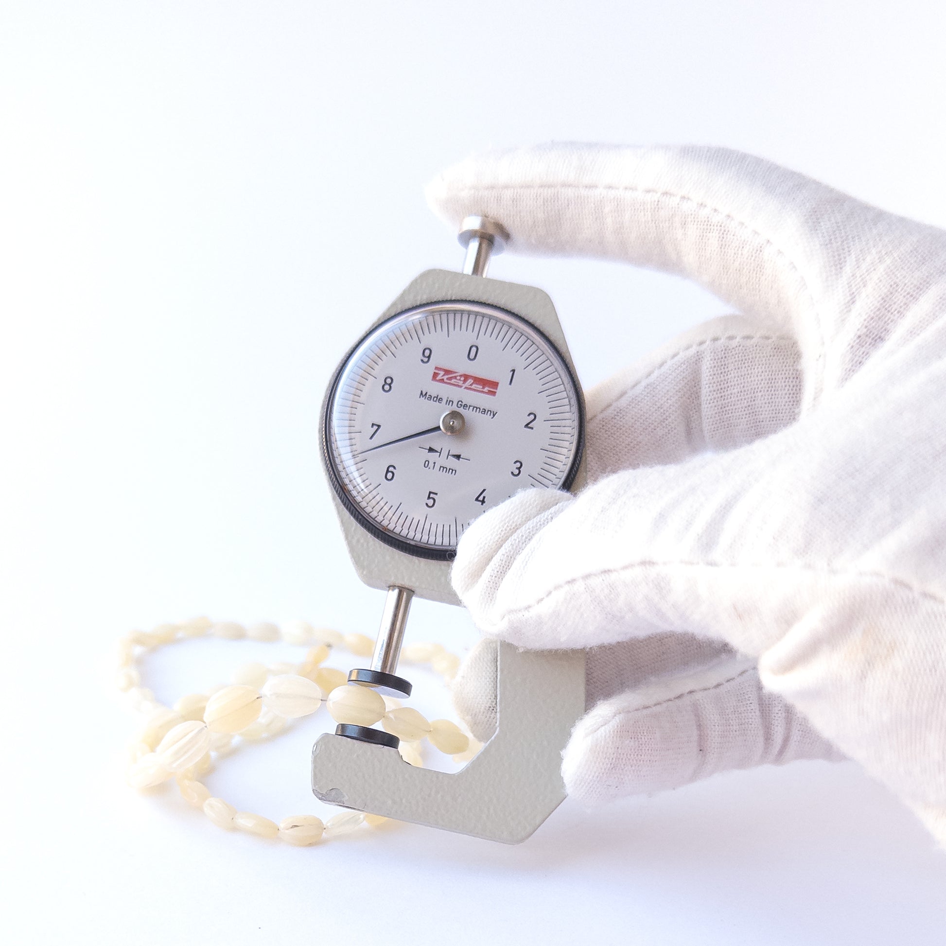 A dial gauge measures the Ethiopian Opal carved oval 5–6mm gemstone.