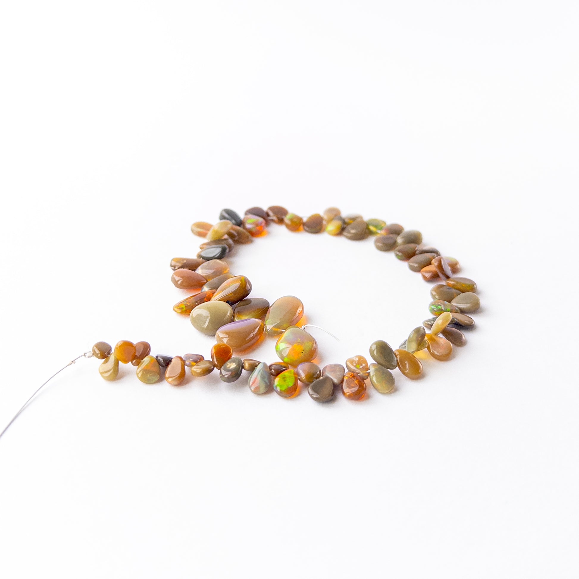 Ethiopian Opal briolette beads showcasing their glossy finish, colour variation and craftsmanship.