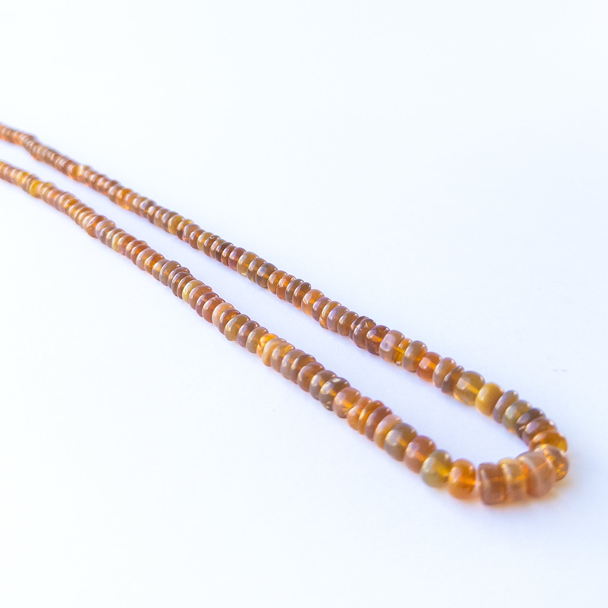 Ethiopian Opal smooth rondelle gemstone beads arranged in a glowing pastel strand for DIY jewellery.