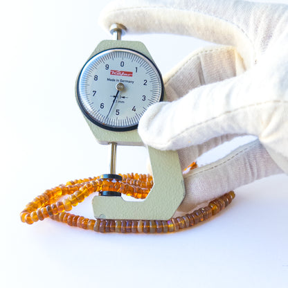 A dial gauge measures the Ethiopian Opal smooth rondelle 4–6mm gemstone.