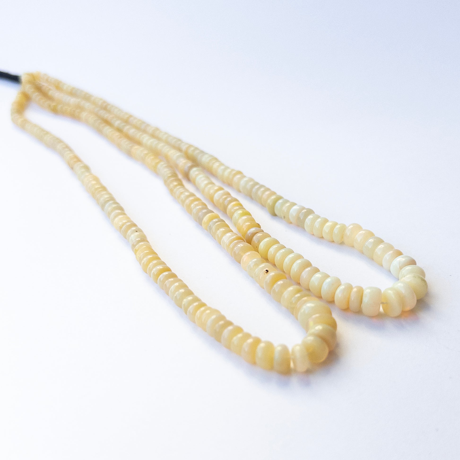 Genuine Ethopian Opal gemstone beads in smooth wheel shape, displaying polish, fire, and natural beauty for jewellery crafting.