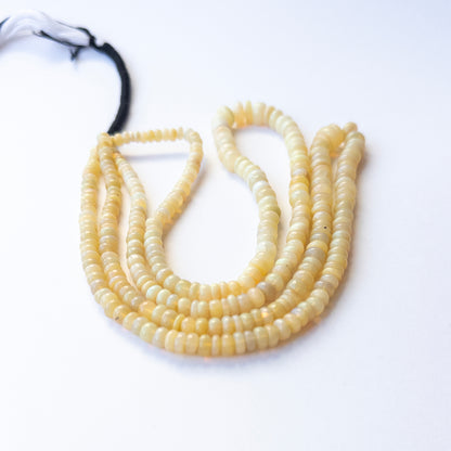 Premium Ethopian Opal gemstone beads in smooth wheel cut arranged in strands, showcasing vibrant flashes for jewellery designers.