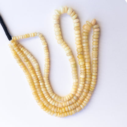 Close‑up of authentic Ethopian Opal smooth wheel stone beads highlighting fire, clarity, and quality for DIY jewellery making.
