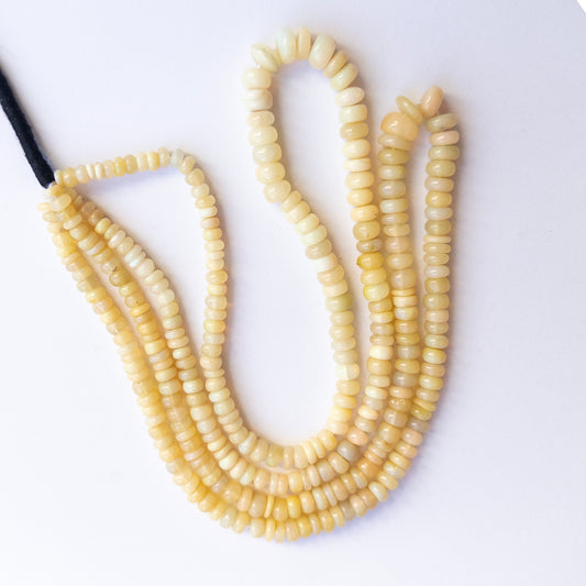 Close‑up of authentic Ethopian Opal smooth wheel stone beads highlighting fire, clarity, and quality for DIY jewellery making.
