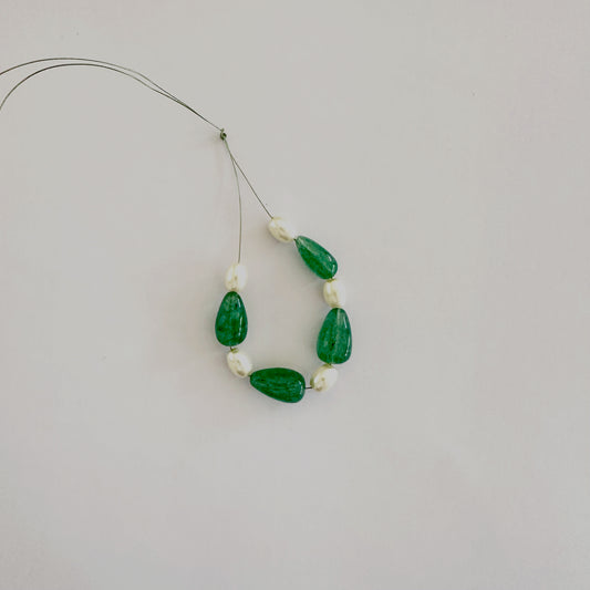 Teardrop Beryl Emerald and oval pearls in a soft gradient layout on velvet fabric.