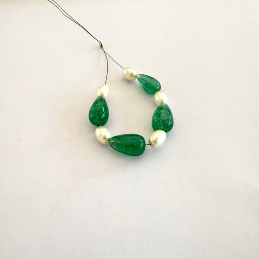 Close-up of glossy emerald beads alongside smooth white pearls in elegant composition.