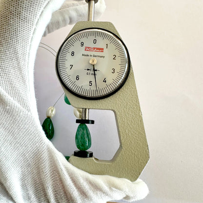 A dial gauge measures the Beryl Emerald teardrop gemstone.