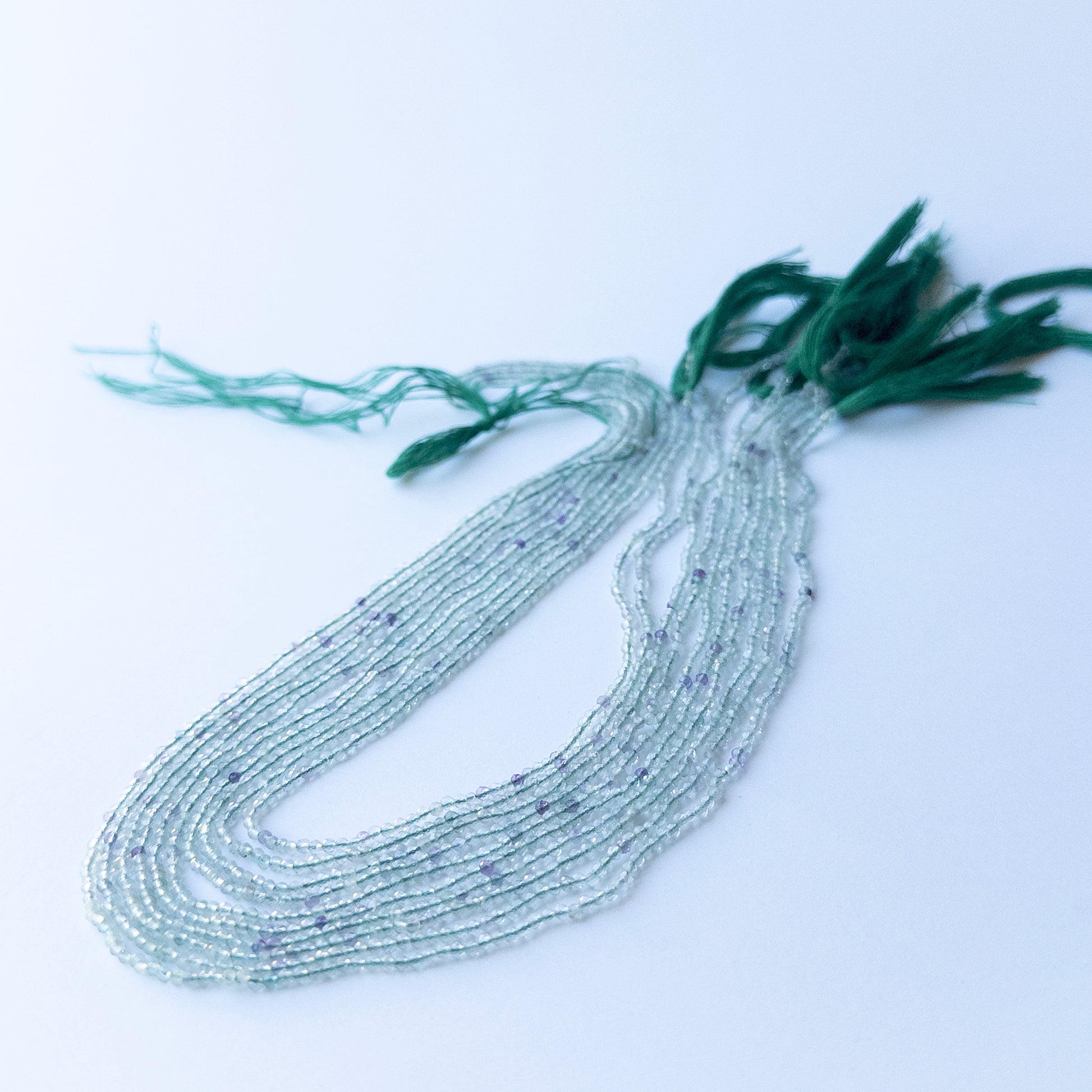 Strand of fluorite faceted rondelles displaying mixed green and purple hues for gemstone beads for DIY jewellery.