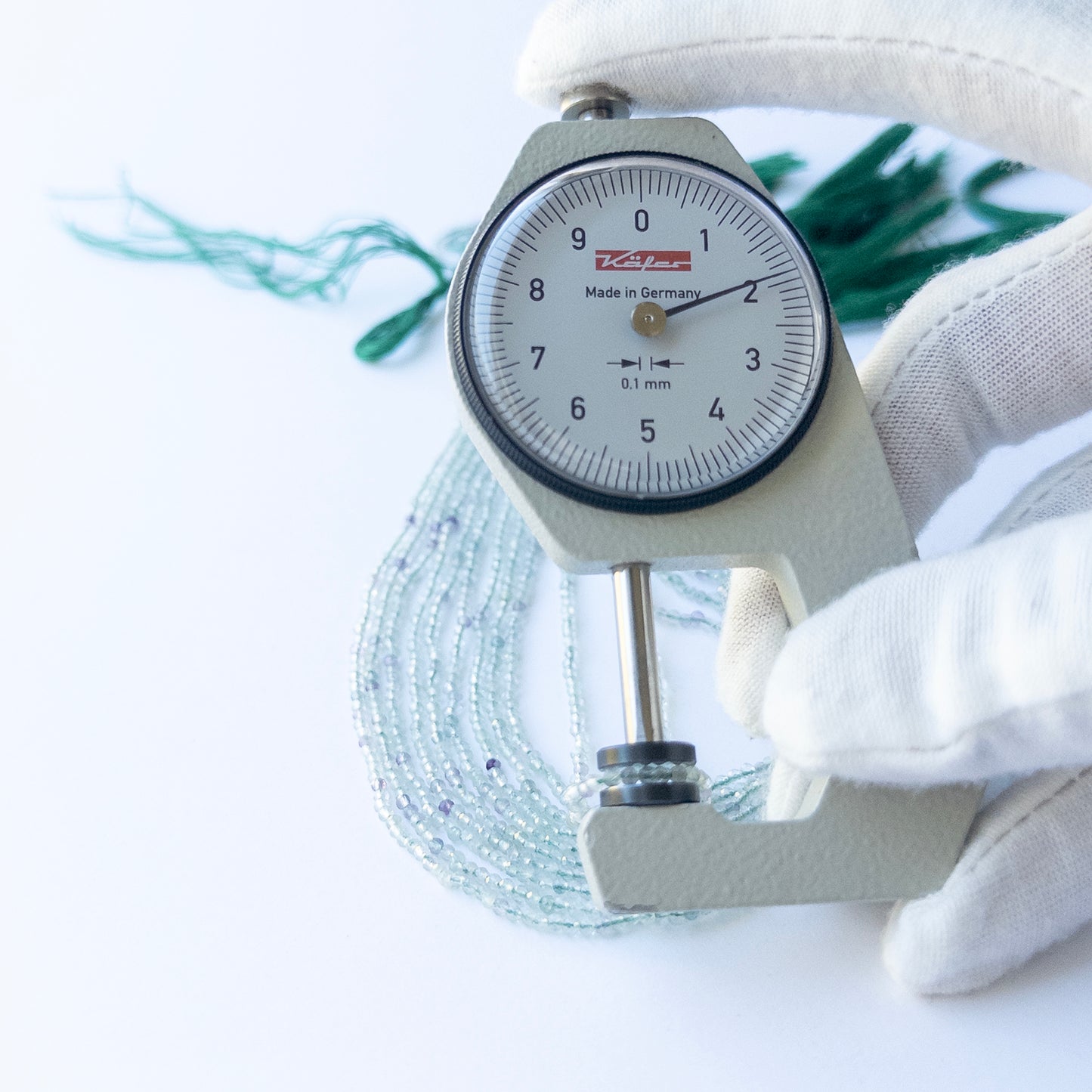 A dial gauge measures the Fluorite Faceted Rondelle 1.9mm gemstone.