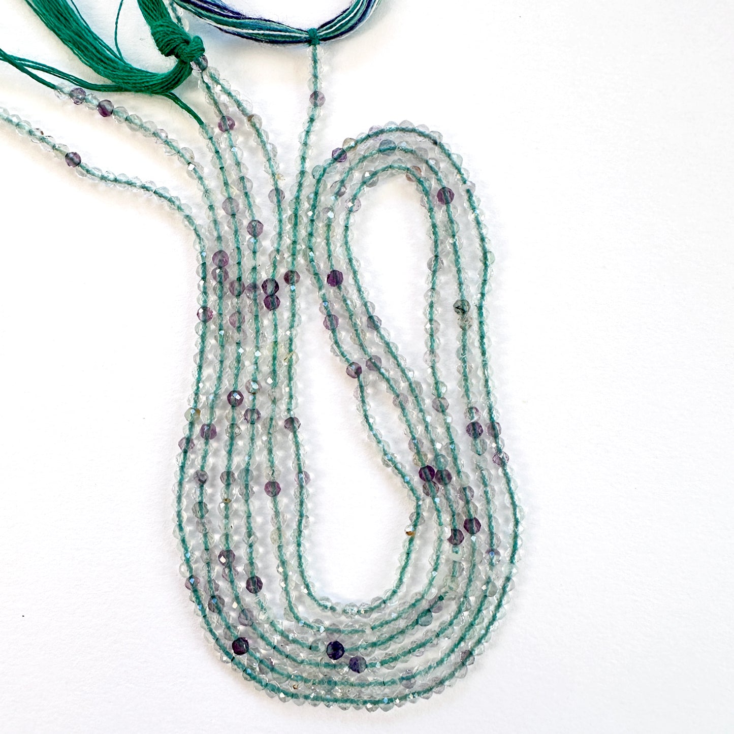 Close-up of Fluorite faceted rondelle beads with mixed purple, green, and clear tones.