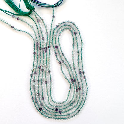 Close-up of Fluorite faceted rondelle beads with mixed purple, green, and clear tones.