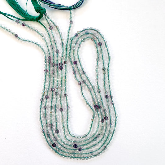 Close-up of Fluorite faceted rondelle beads with mixed purple, green, and clear tones.