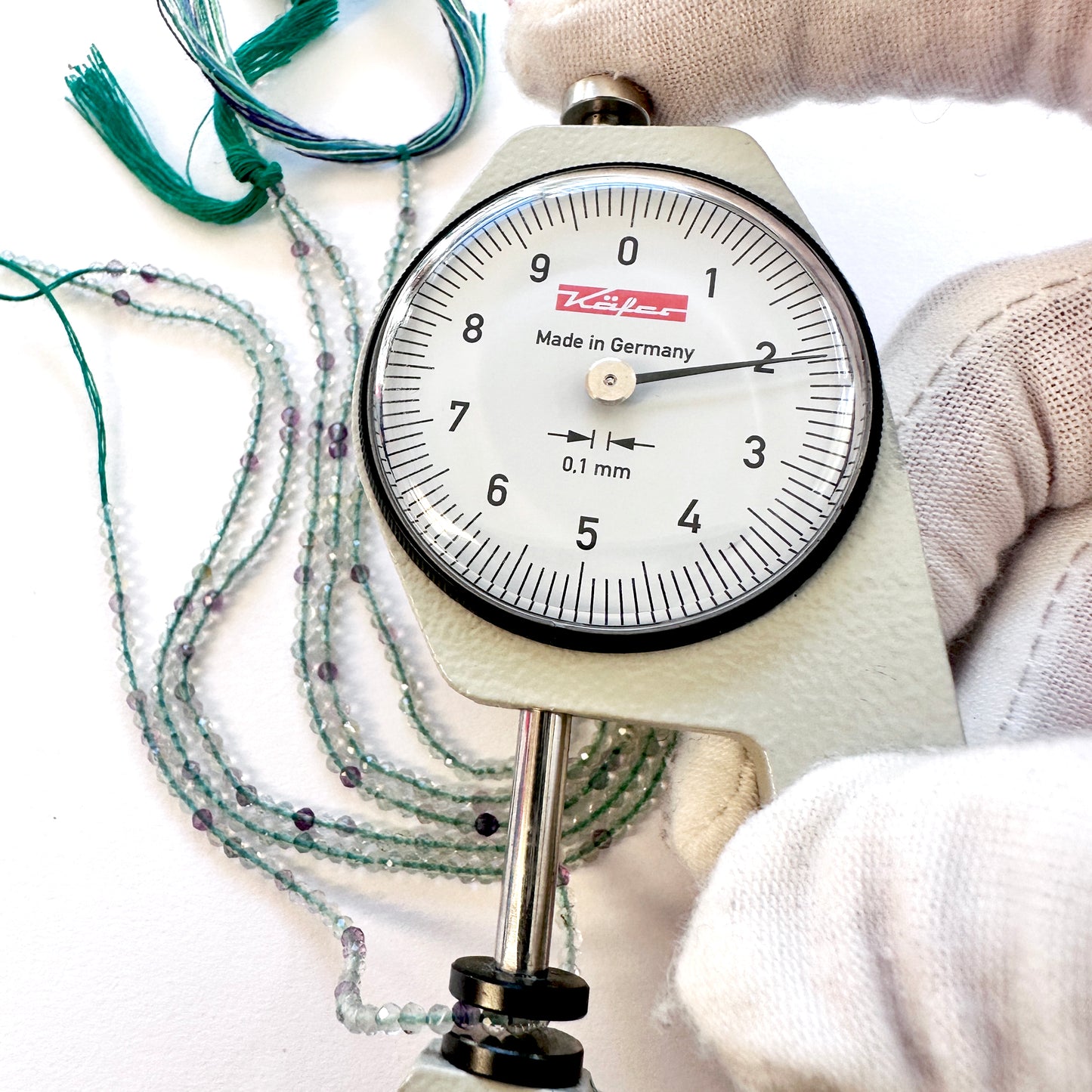 A dial gauge measures the Fluorite faceted rondelle 2-2.2mm gemstone.