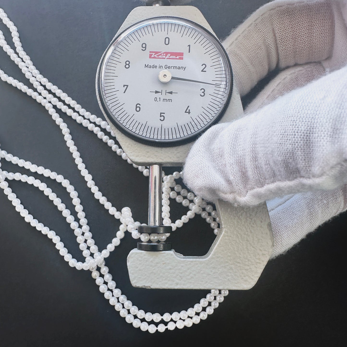 A dial gauge measures the Freshwater Pearl smooth round 2.6-2.7mm gemstone.