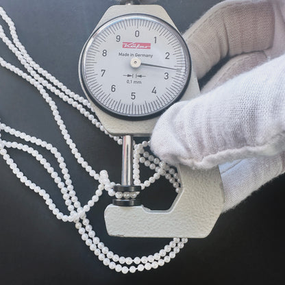 A dial gauge measures the Freshwater Pearl smooth round 2.6-2.7mm gemstone.